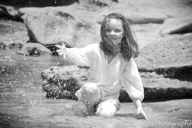 Little girl splashing water at fair light beach - family portrait photography sydney